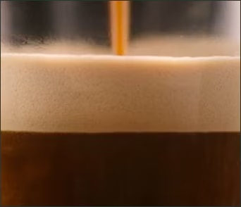 Zbliżenie na kawę Starbucks nalewaną do filiżanki podczas parzenia.
